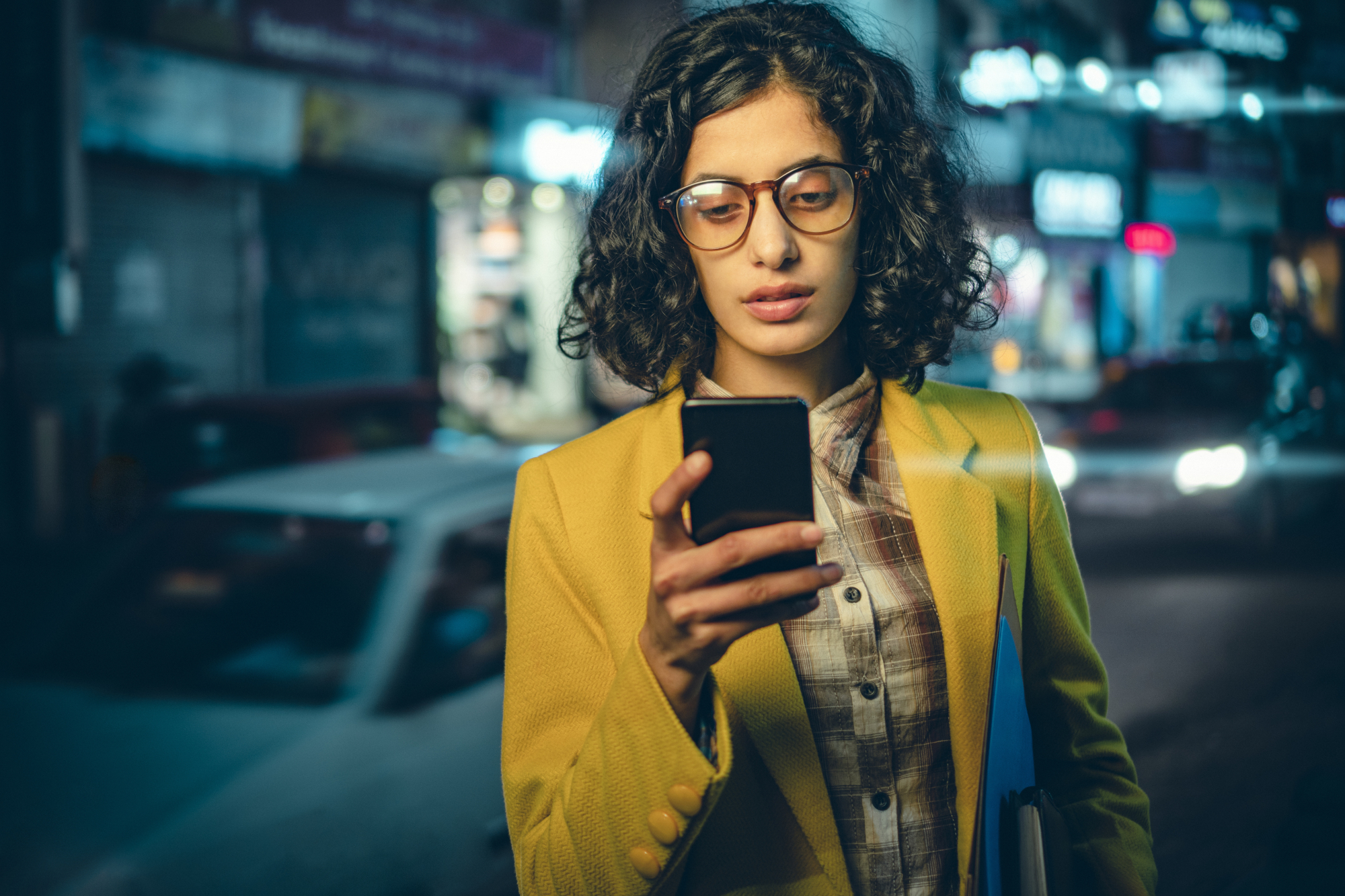 Business woman using phone on a busy road at night