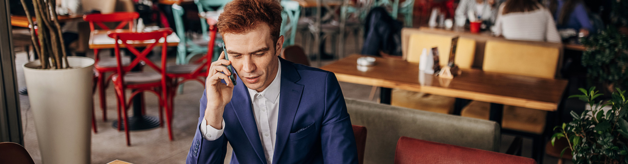 Business man using laptop and phone at cafe