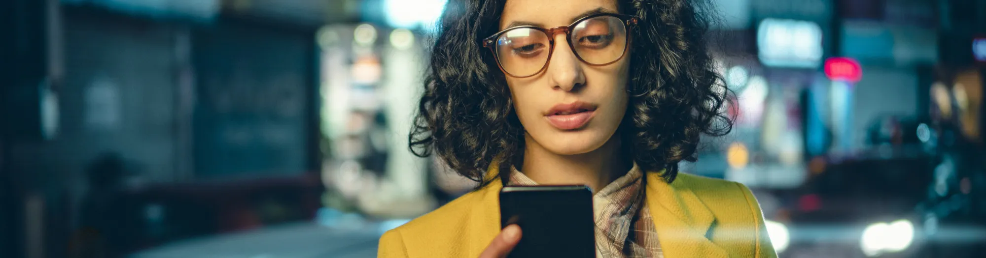 Business woman using phone on a busy road at night