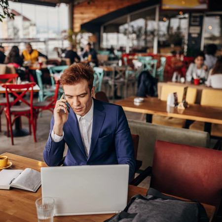 Business man using laptop and phone at cafe