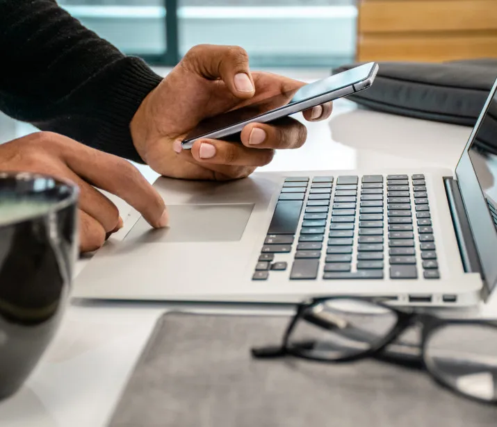 Man using laptop and mobile phone on desk